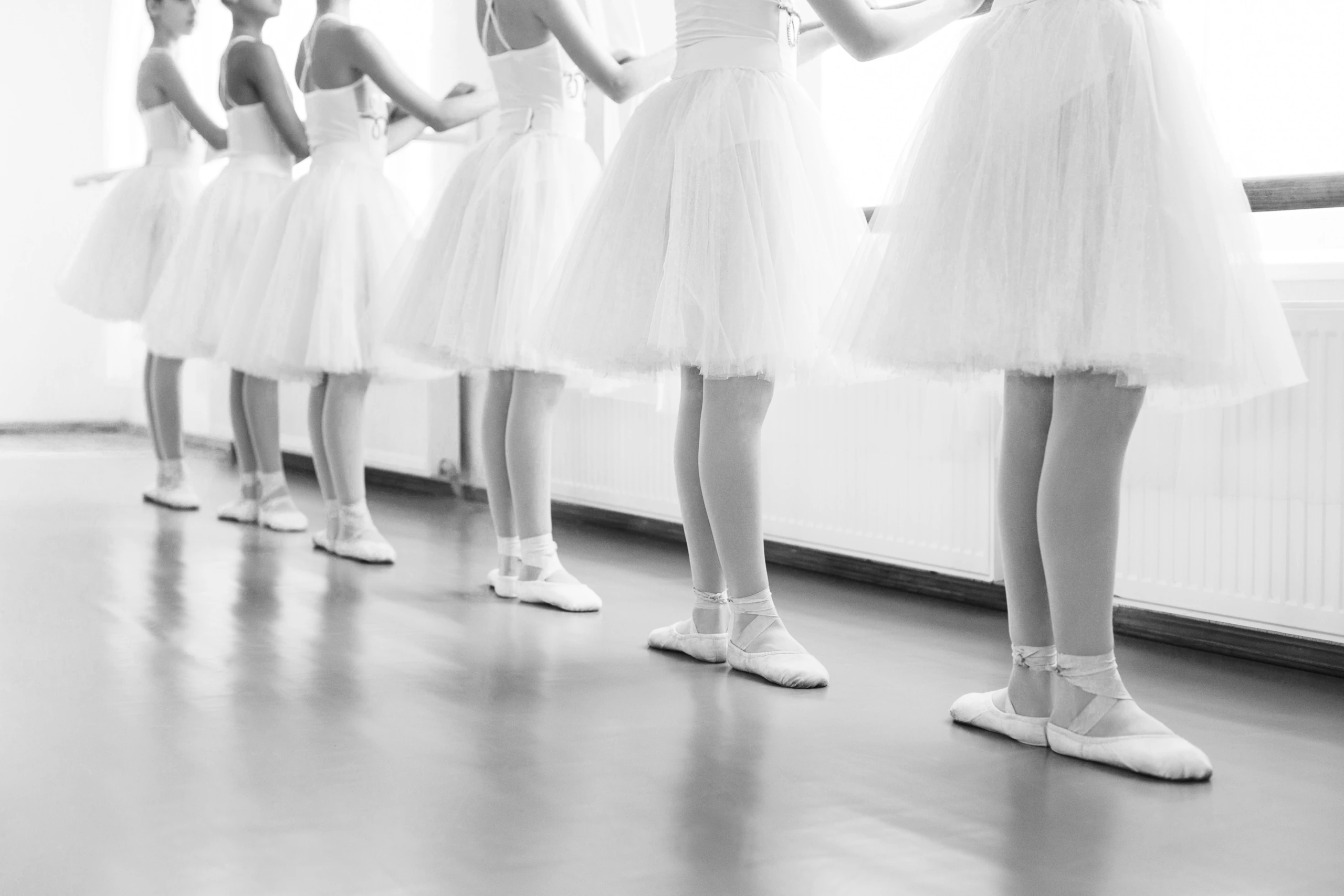 Row of young dancers in white tutus at the barre